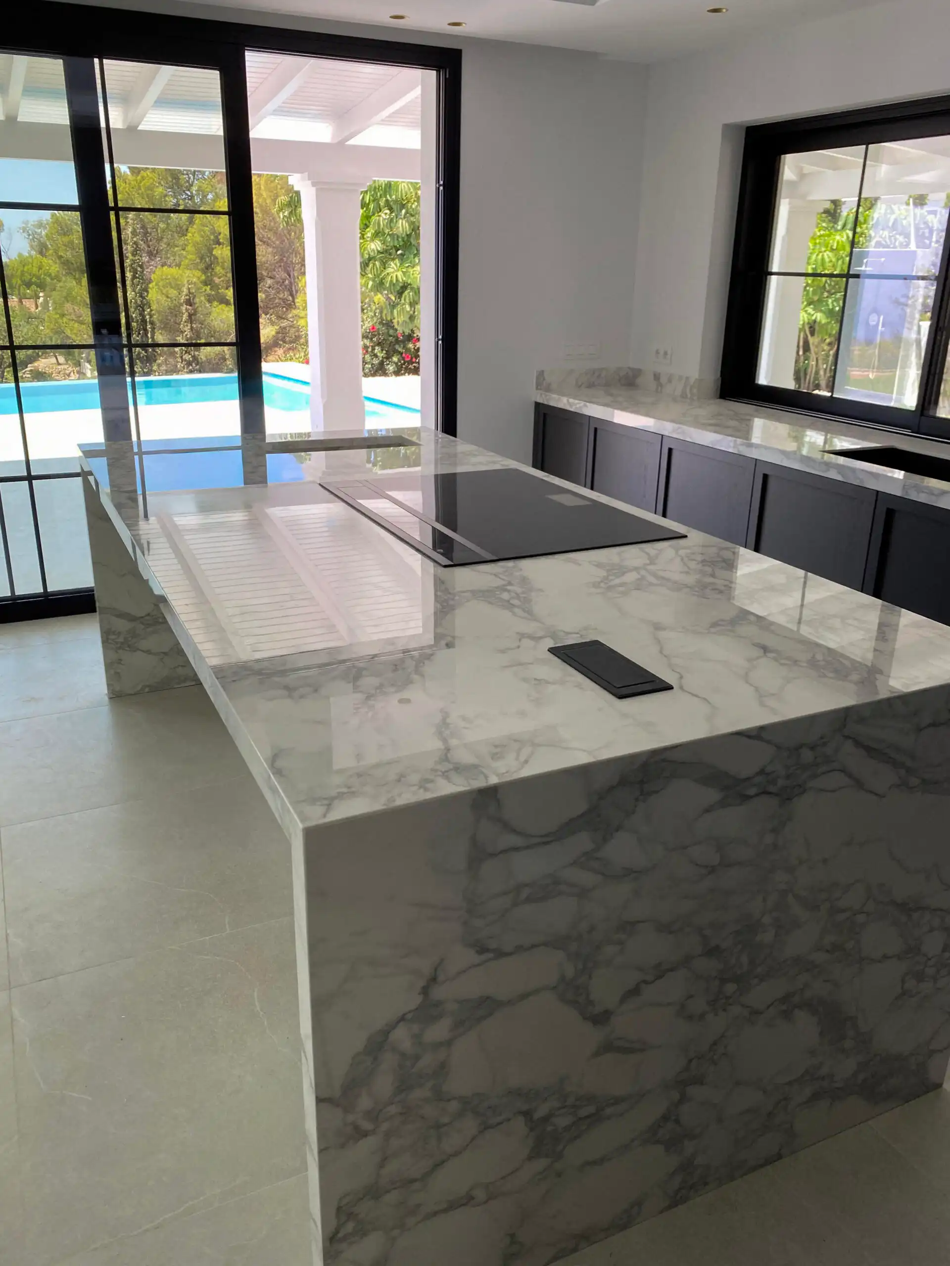 Kitchen island with marble counter and black-framed windows